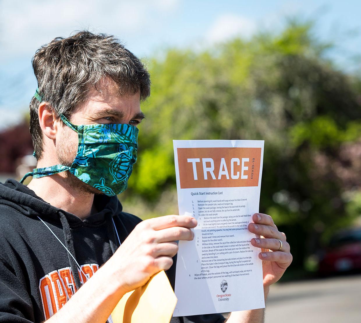 Ben Dalziel reading TRACE document with mask on.