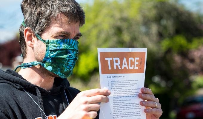 Ben Dalziel reading TRACE document with mask on.