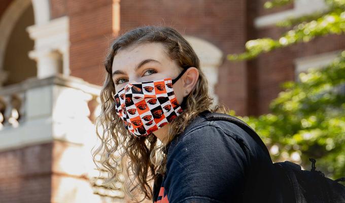 OSU student wearing a mask in front of Weatherford Hall.